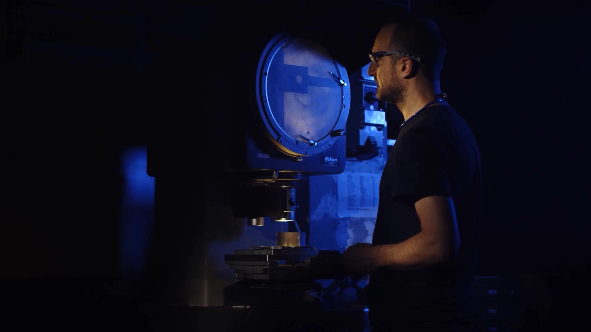 Operatore al microscopio in luce blu durante la produzione di un video aziendale